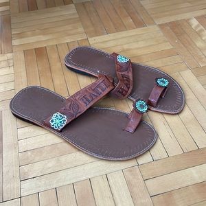 Brown shoes that’s says Haiti with art flower on the side strap